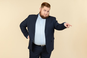 Unzufriedene junge übergewichtige mann in anzug zeigt