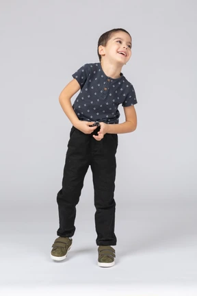 Front view of a happy boy in casual clothes looking up