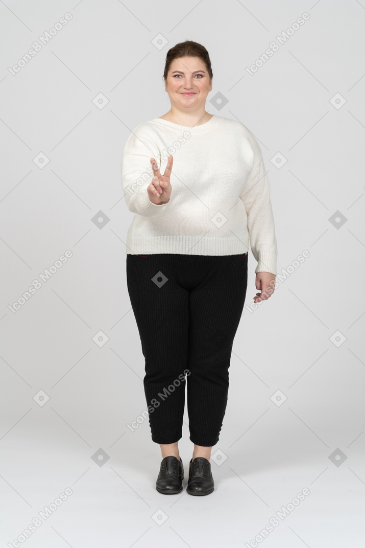 Femme dodue dans des vêtements décontractés montrant un signe de paix