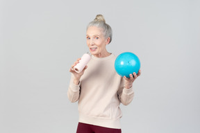 Old woman holding light blue ball and sports bottle
