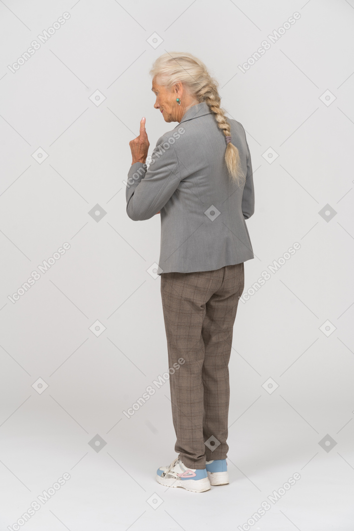 Rear view of an old lady in suit making a warning sign