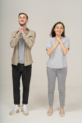 Joyeux jeune couple souriant avec les mains sur la poitrine