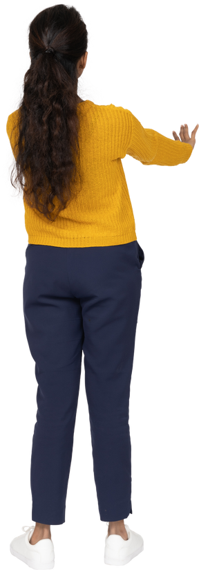 Vista posterior de una niña en ropa casual mostrando gesto de parada
