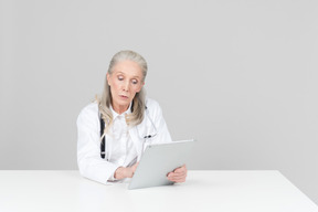 Aged female doctor working on a digital tablet