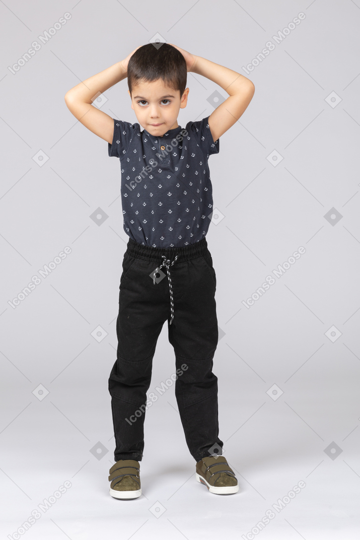 Vista frontal de um lindo menino posando com as mãos atrás da cabeça