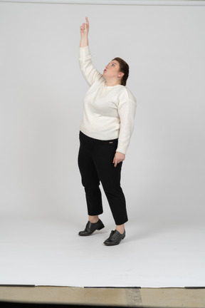 Front view of a plus size woman in casual clothes standing with raised arm