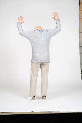 Мужчина стоит с поднятыми руками и спиной к камере