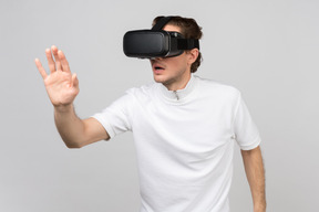 Young man in virtual reality headset touching something invisible