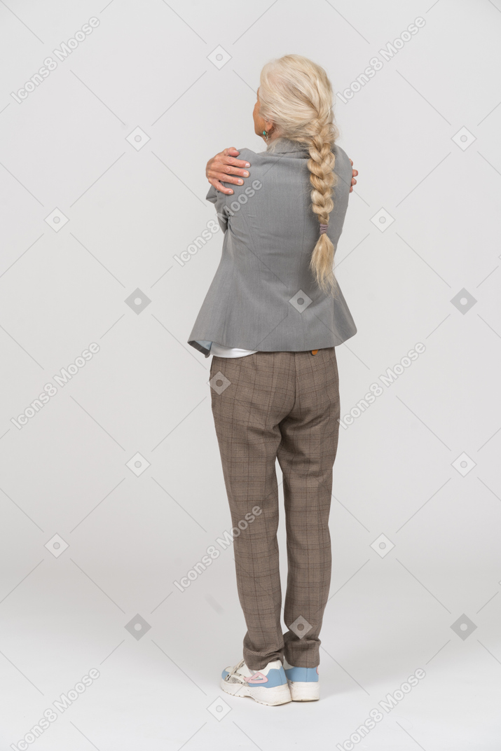 Back view of an old lady in suit hugging herself