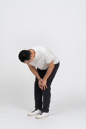 Front view of a man bending down and touching hurting knee