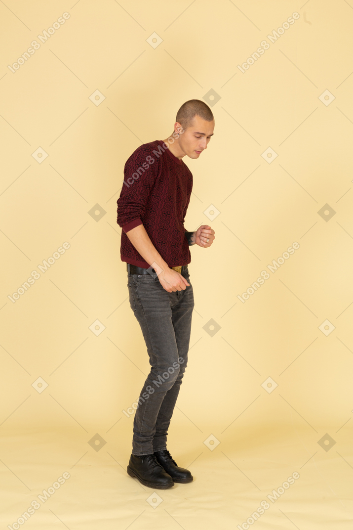Вид в три четверти усталого танцующего молодого человека в красном пуловере