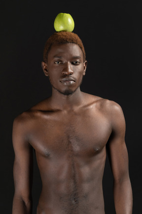 Close-up an african male standing confidently with an apple on his head