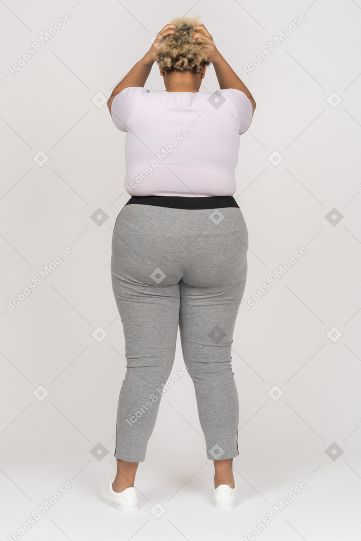Body positive black woman holding head with both arms back to camera