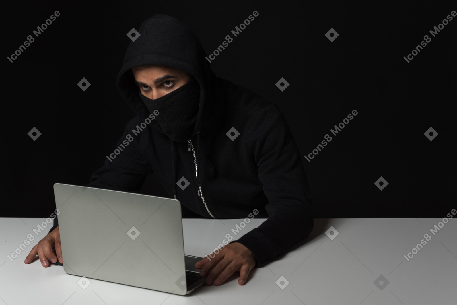 Hacker guy sitting at the table and working on laptop in the dark