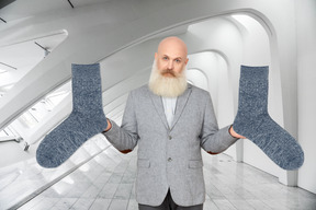 A man with a long beard holding up two socks