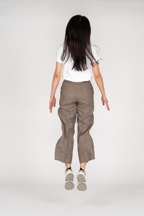 Vista traseira de uma jovem saltitante de calça e camiseta