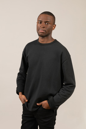 Young man in black outfit keeping hands in pockets