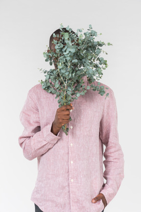 Good looking young man holding green branches