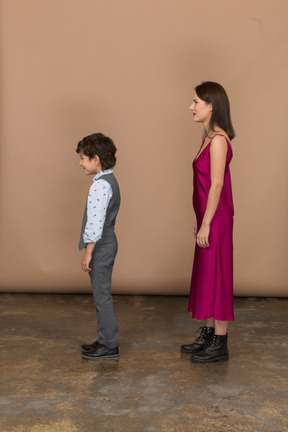 Woman in red dress and little boy standing in profile