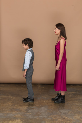 Femme en robe rouge et petit garçon debout de profil