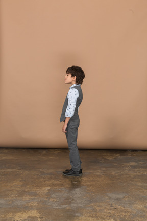 Boy in grey suit standing in profile