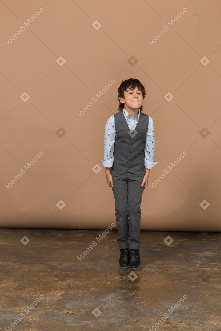 Front view of a cute boy in suit jumping