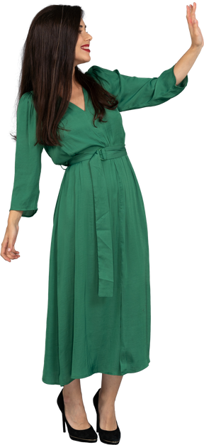 Vista di tre quarti di una giovane donna di saluto in abito verde