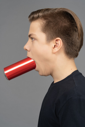 Side view of a man with red can in his mouth