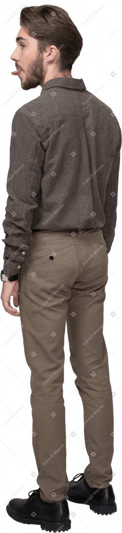 Vista posteriore di tre quarti di un giovane uomo in abiti da ufficio che mostra la lingua