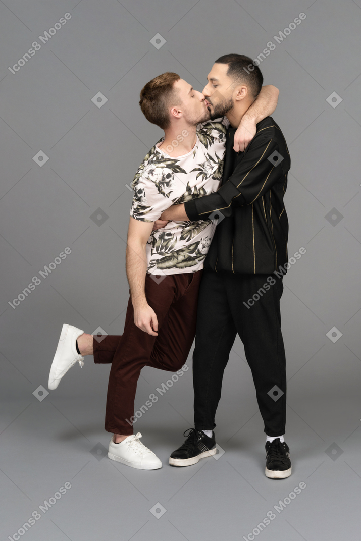 Two young men hugging lightly and kissing