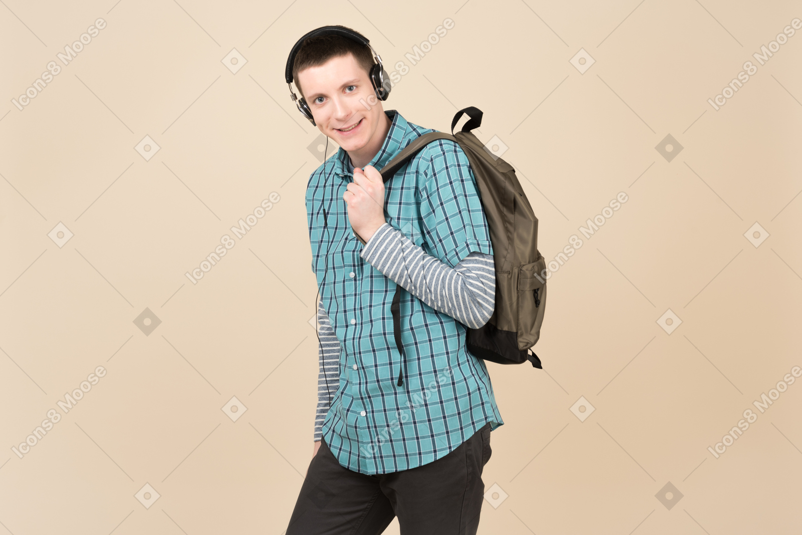 Student, der mit einem rucksack und kopfhörern steht