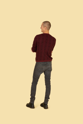 Back view of a displeased young man dressed in casual clothes crossing his hands