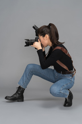 Young woman taking pictures while sitting sideways to camera