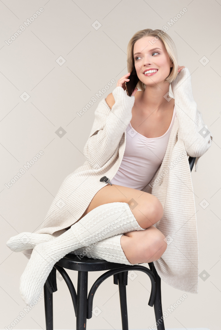 電話での会話に関わる若い女性が椅子に座って
