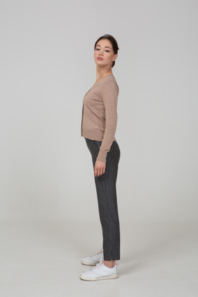 Side view of a young lady in pullover and pants turning head