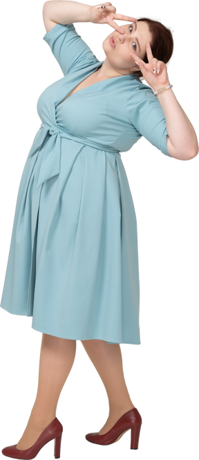 Вид сбоку женщины в синем платье, показывающей знаки v