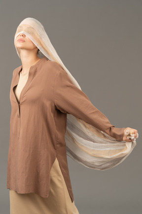Mujer joven posando con una bufanda que cubre sus ojos