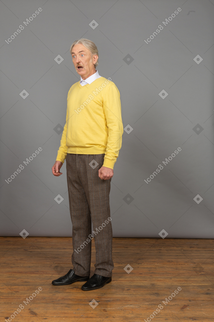 Three-quarter view of a talking man in a yellow pullover with his mouth open