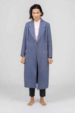 Angry woman in coat standing with clenched fists