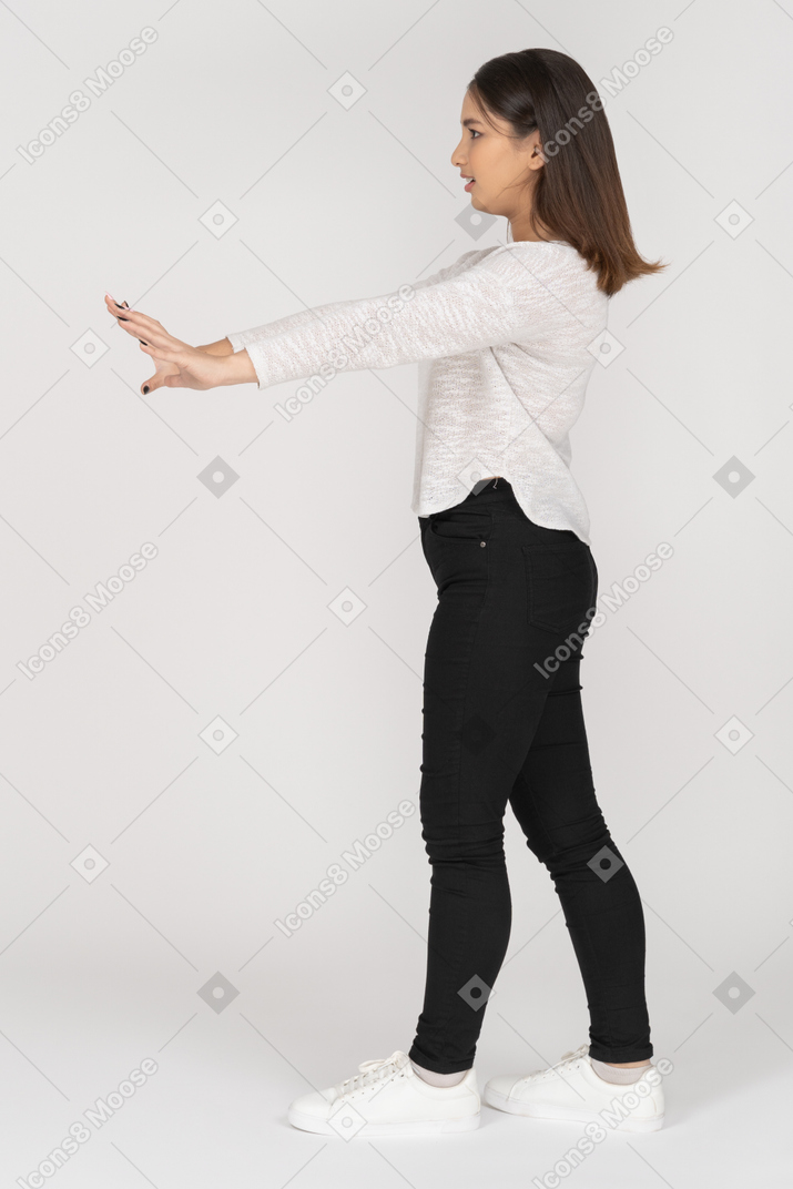 Giovane donna seria in piedi con le braccia aperte di profilo