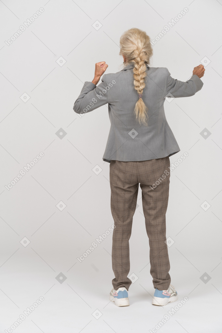 Back view of an impressed old lady in suit explaining something
