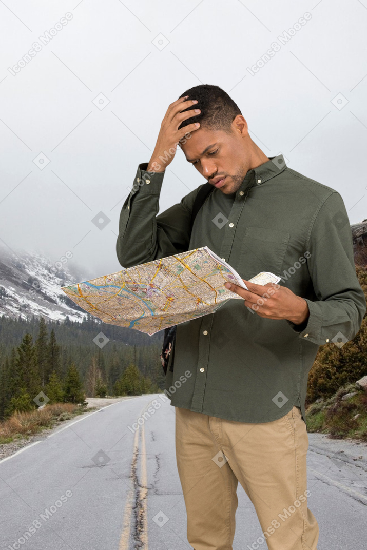 A man standing on the side of a road looking at a map