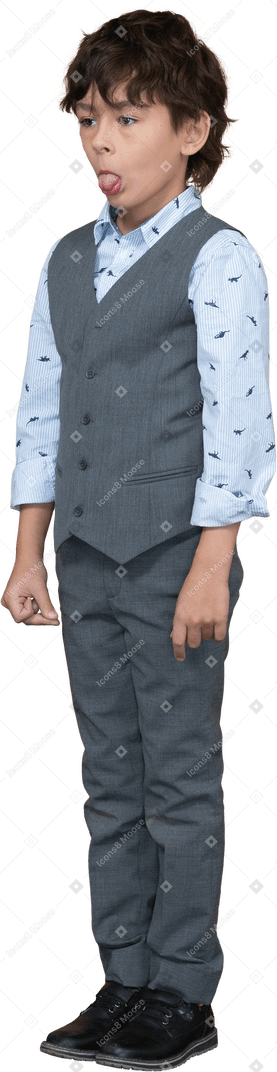 Vista frontale di un ragazzo carino in abito grigio che mostra la lingua