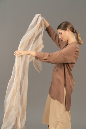 Side view of a young woman holding linen striped scarf