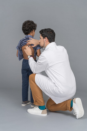 Médico com estetoscópio examinando um menino