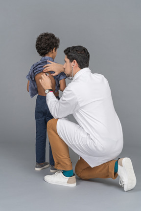 Médico con estetoscopio examinando a un niño