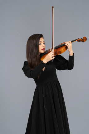 Close-up de uma jovem de vestido preto tocando violino