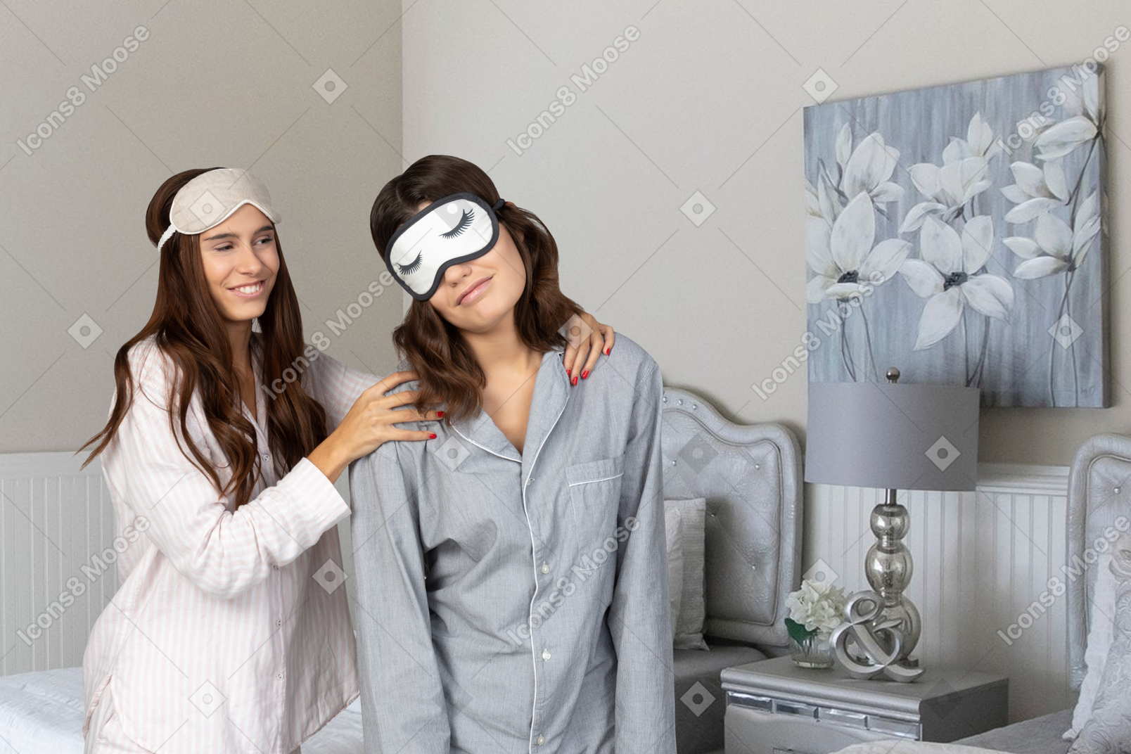 Two women in pajamas with blindfolds on their faces
