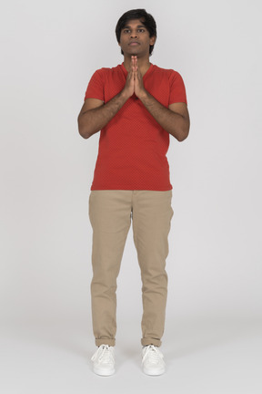 Young man looking straight with praying hands