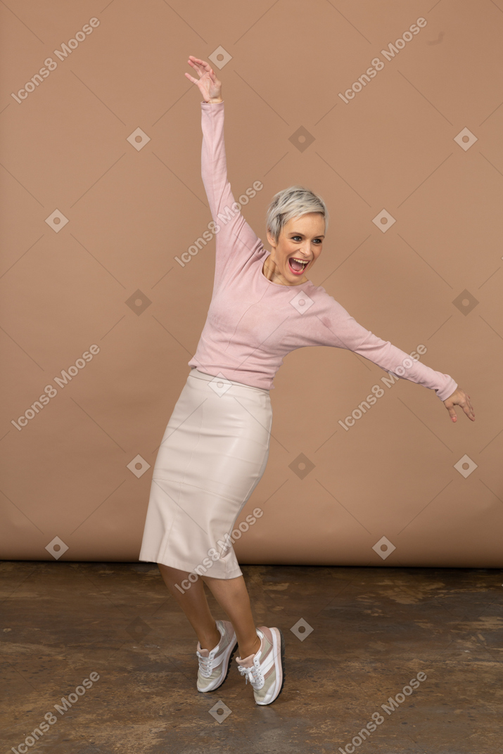 Vista frontal de uma mulher feliz em roupas casuais, na ponta dos pés